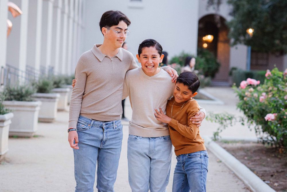 A family walks together in matching casual outfits along a white columned walkway.