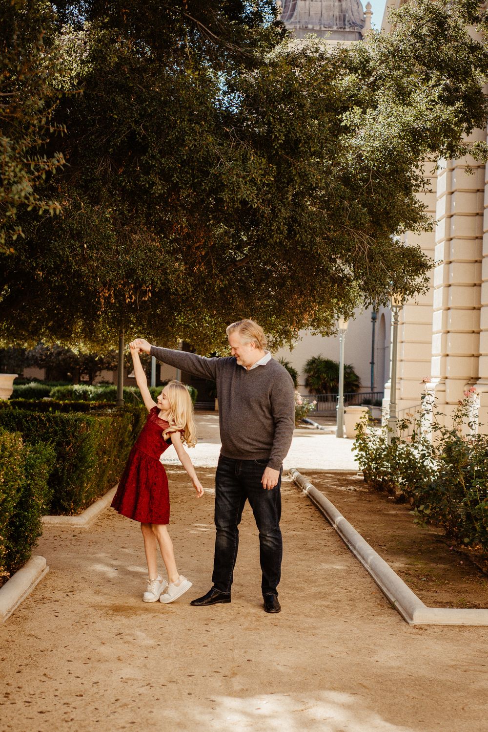 A dance twirl moment captured in a formal garden setting with classical architecture.