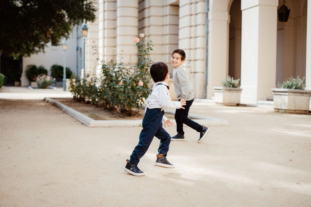 People play and interact in front of a classic white columned building facade.