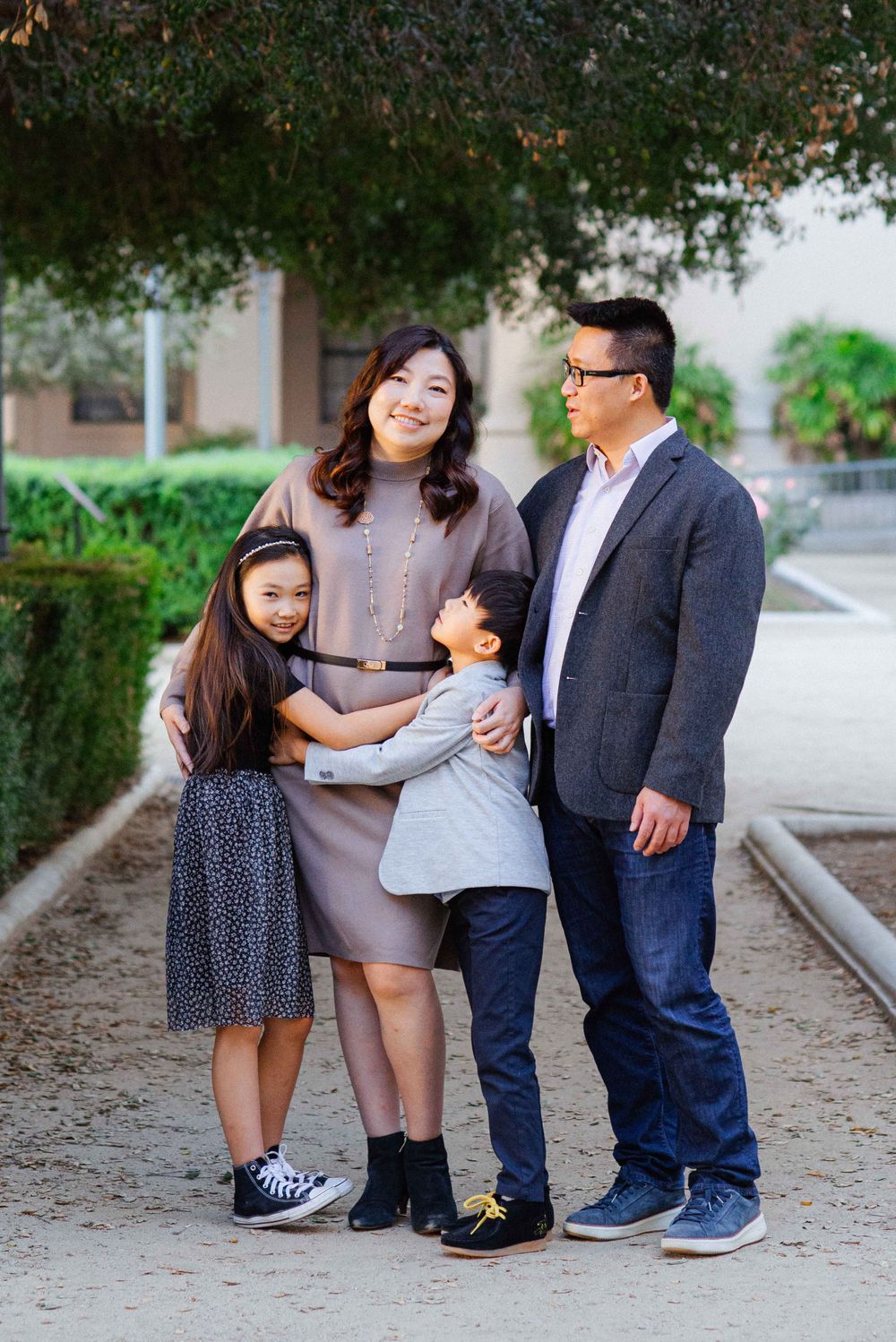 A family group poses together in casual attire against a garden background.