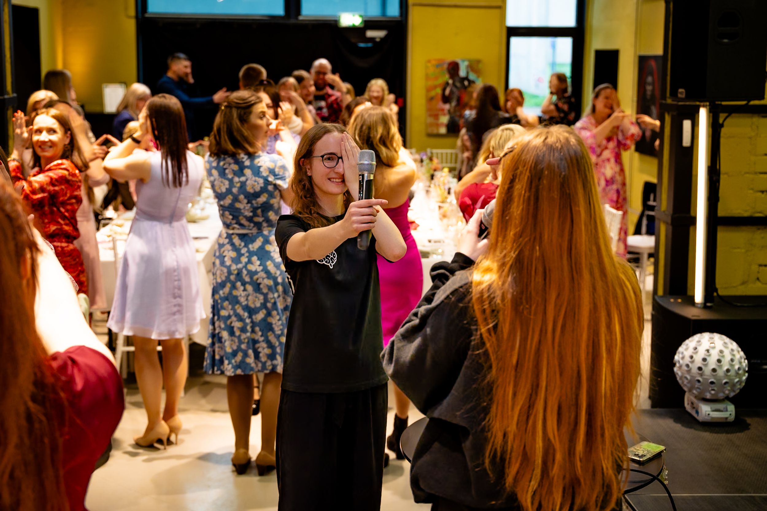 Women socializing at an elegant indoor event, with one guest taking a selfie in a festive, well-lit venue.