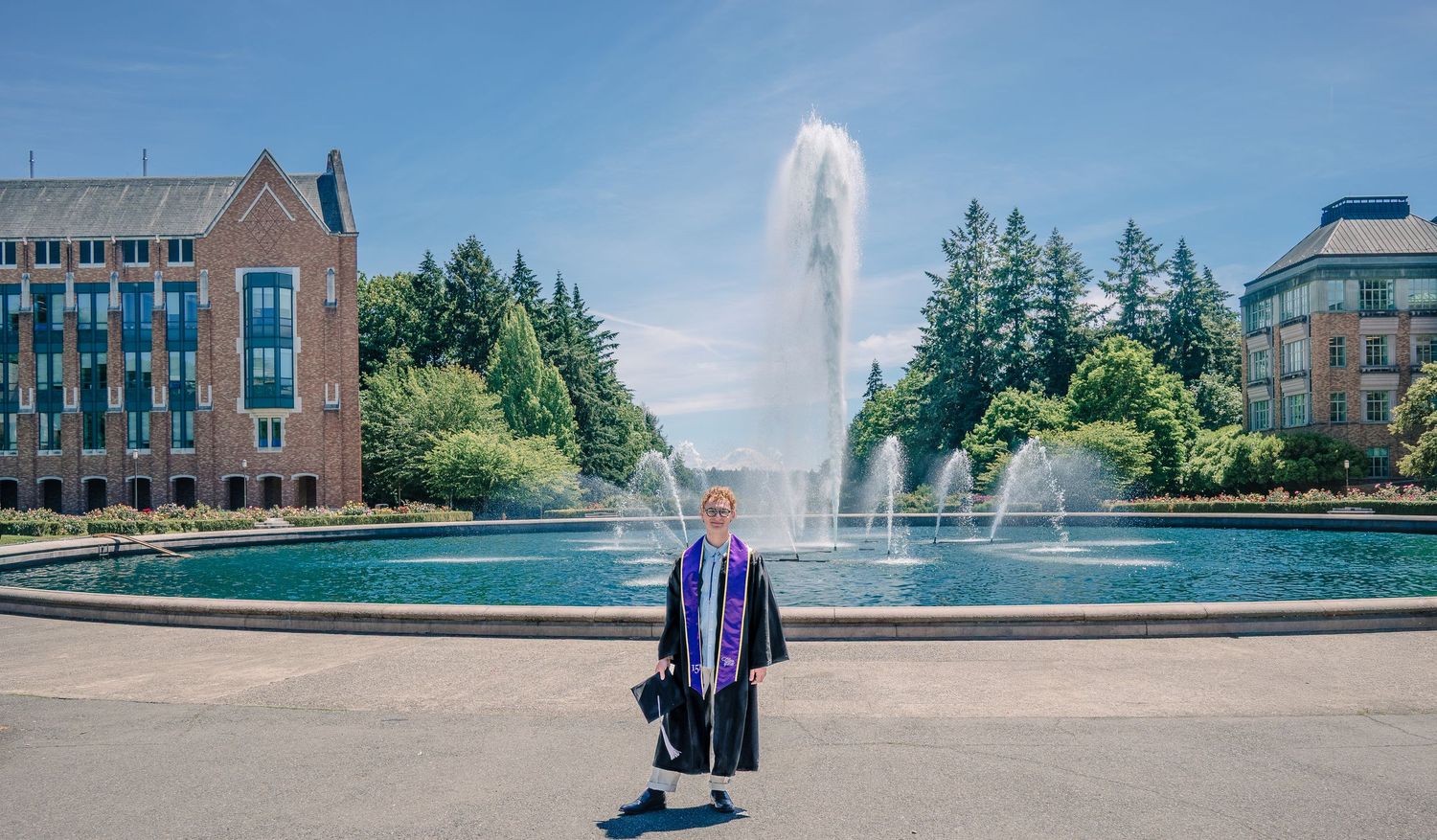 Graduate standing in front of Drumheller Fountain during University of Washington commencement season