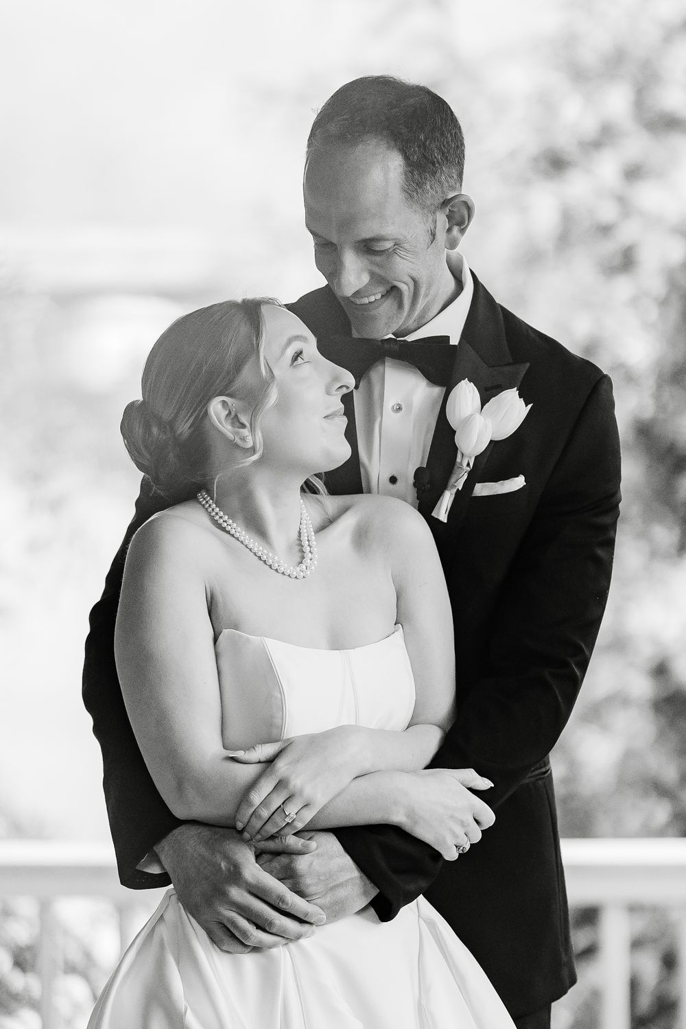 Black and white portrait of bride and groom embracing and smiling at each other on wedding day.
