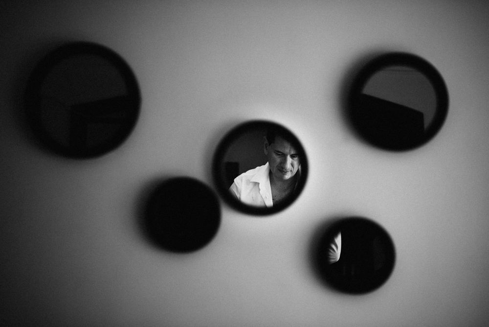 Black and white photo of circular mirrors on a wall reflecting a person's portrait in artistic composition.