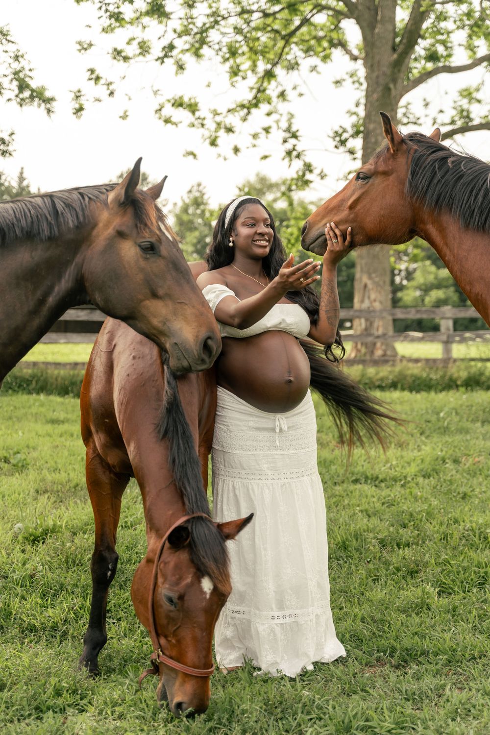 Maternity photo of mom-to-be wearing a white 2 piece outfit with horses