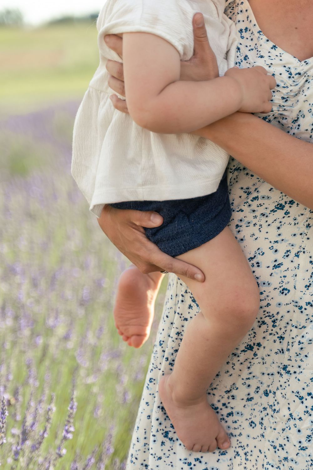 Mom and baby detail photo, mom is holding the baby and the focus is on moms hands and baby's feet
