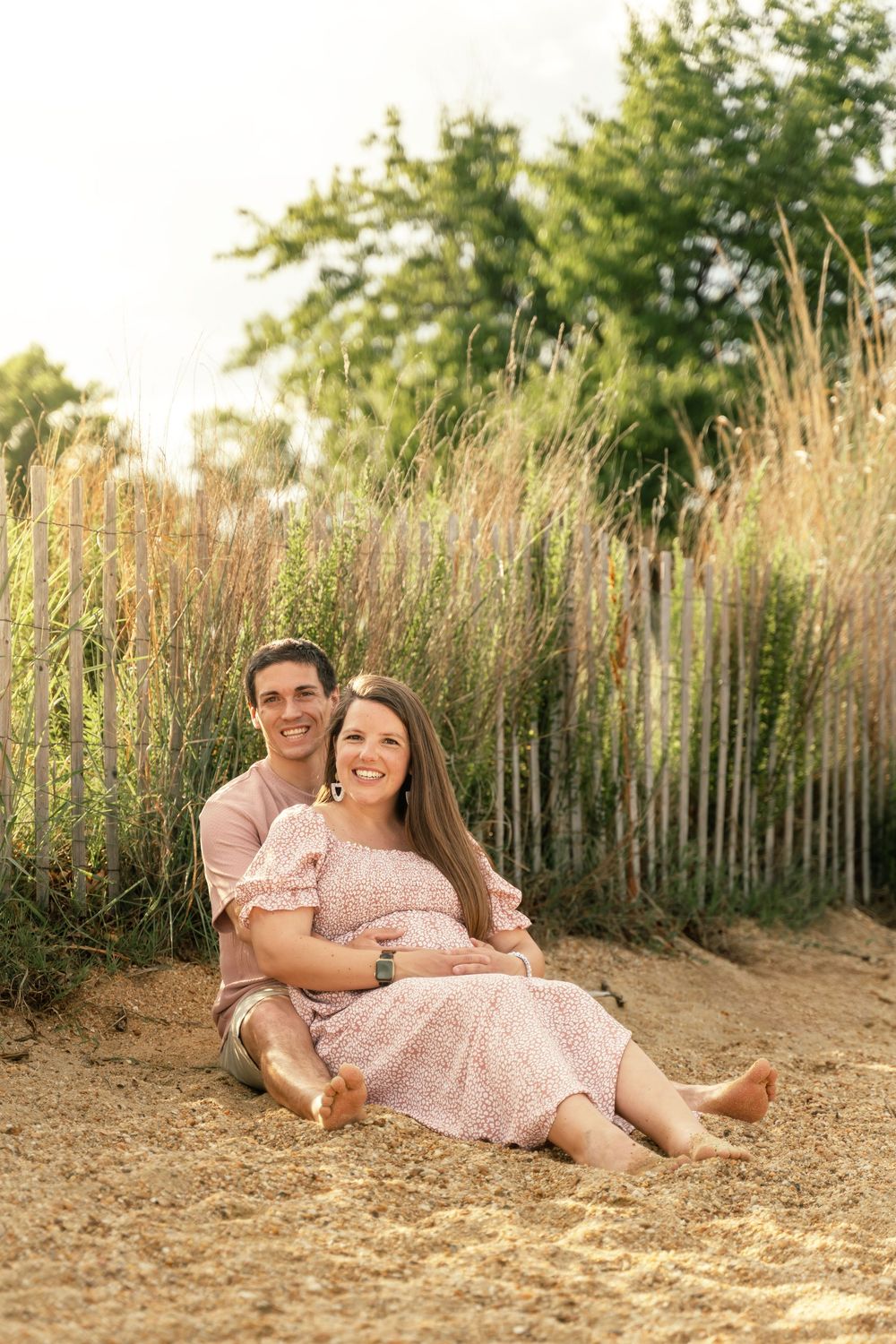 Maternity photoshoot on the beach, mom and dad to-be sitting in the sand
