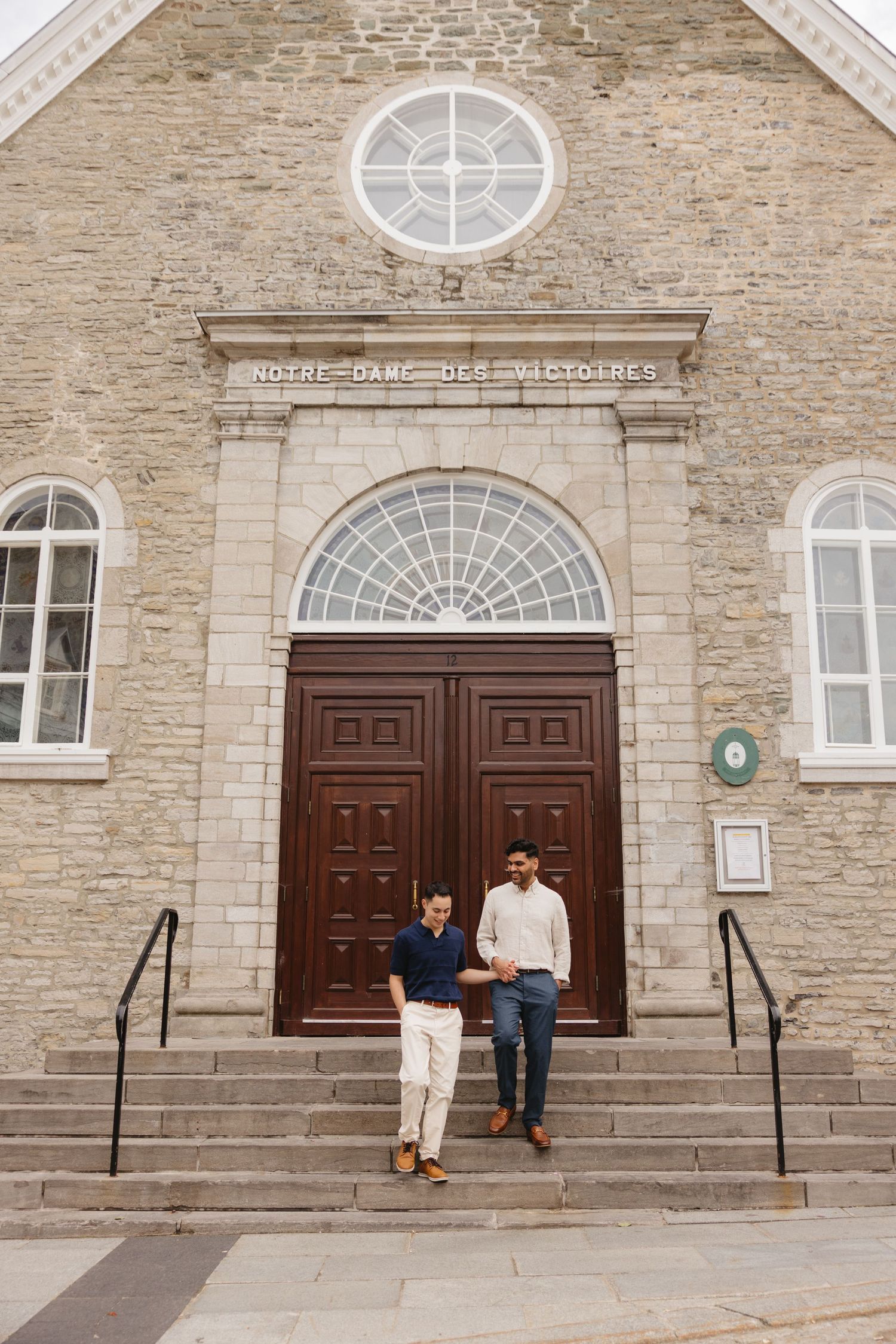 Two men standing on steps outside Notre-Dame-des-Victoires church in Quebec City, Canada.