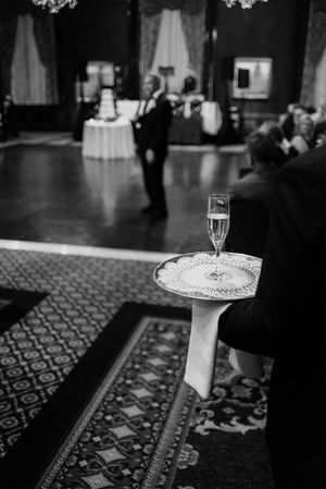 Black and white photo of champagne flute on silver tray at elegant wedding reception.