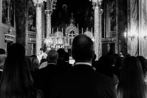 Black and white photo of wedding guests standing in an ornate church during a ceremony.