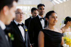 Wedding party in formal attire, groomsmen in tuxedos with bow ties and bridesmaids in black dresses at an elegant ceremony.