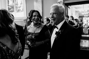 Black and white photo of elegantly dressed couple smiling and socializing at a formal wedding reception event.