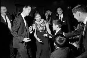 Black and white photo of elegantly dressed adults and children dancing together at a formal wedding reception.