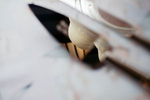 Close-up of artist paintbrushes and palette knife resting on a paint-splattered white canvas surface.
