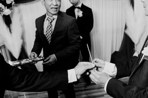 Black and white photo of men in suits exchanging rings during a formal wedding ceremony.