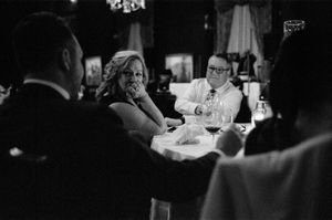 Black and white photo of elegantly dressed guests socializing at a formal dinner party event.