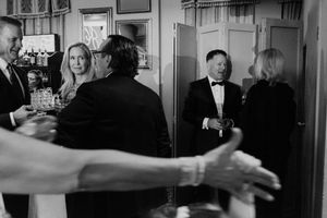 Black and white photo of elegantly dressed guests socializing at a formal wedding reception event.