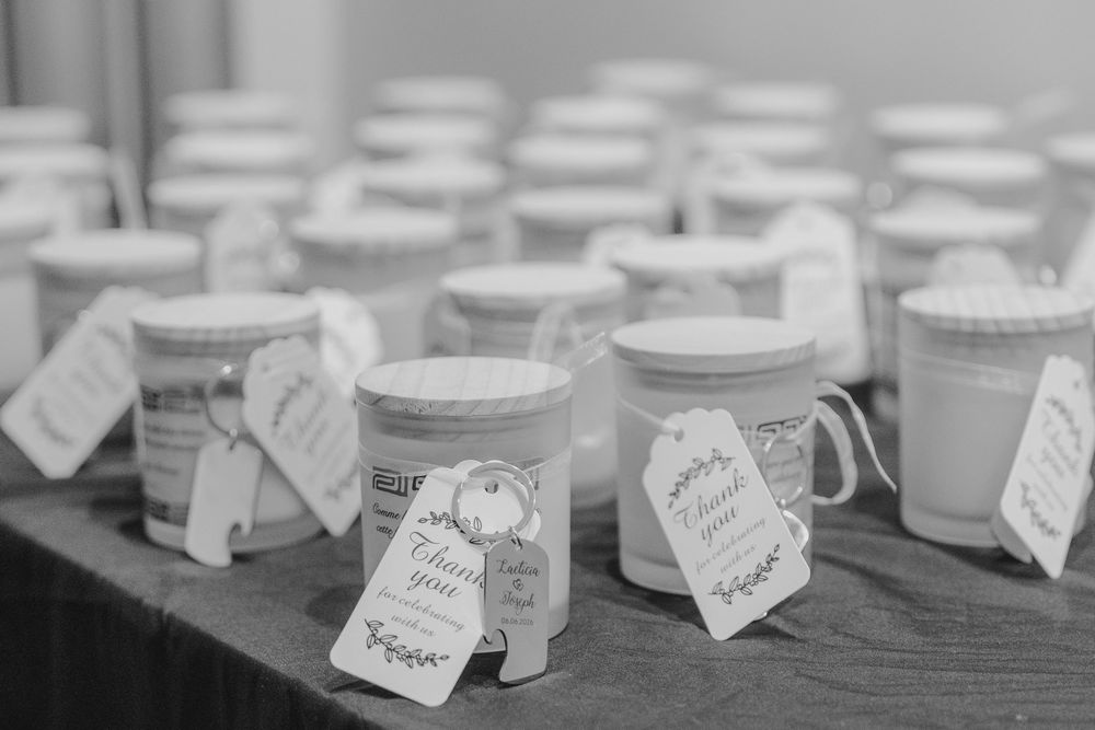 Black and white photo of mason jar wedding favors with gift tags displayed on a table.