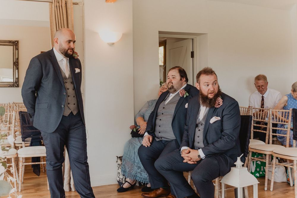 Three groomsmen in navy suits waiting before a wedding ceremony in an elegant venue.