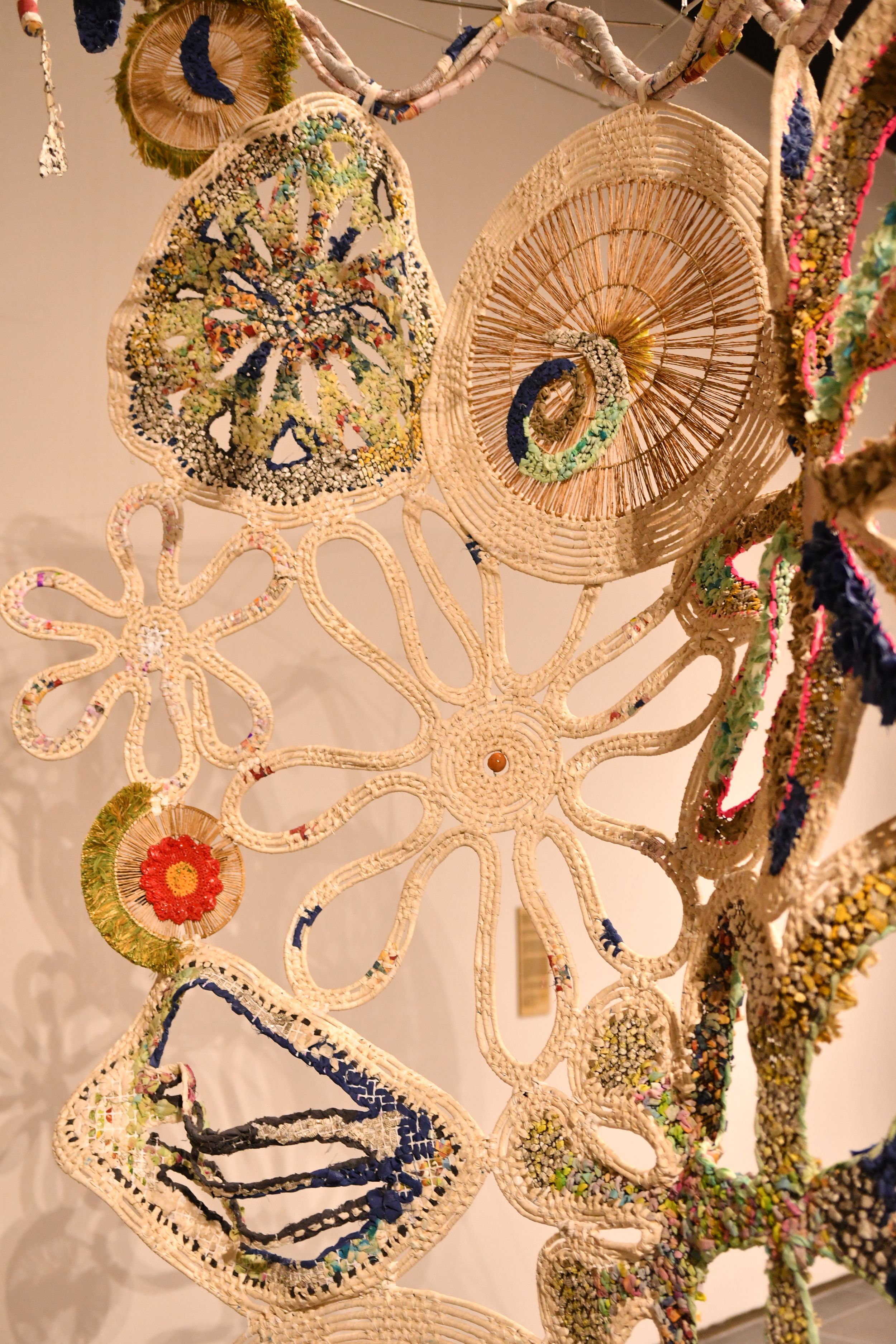 Intricate handcrafted crochet art installation featuring floral and organic shapes in cream and multicolor threads.