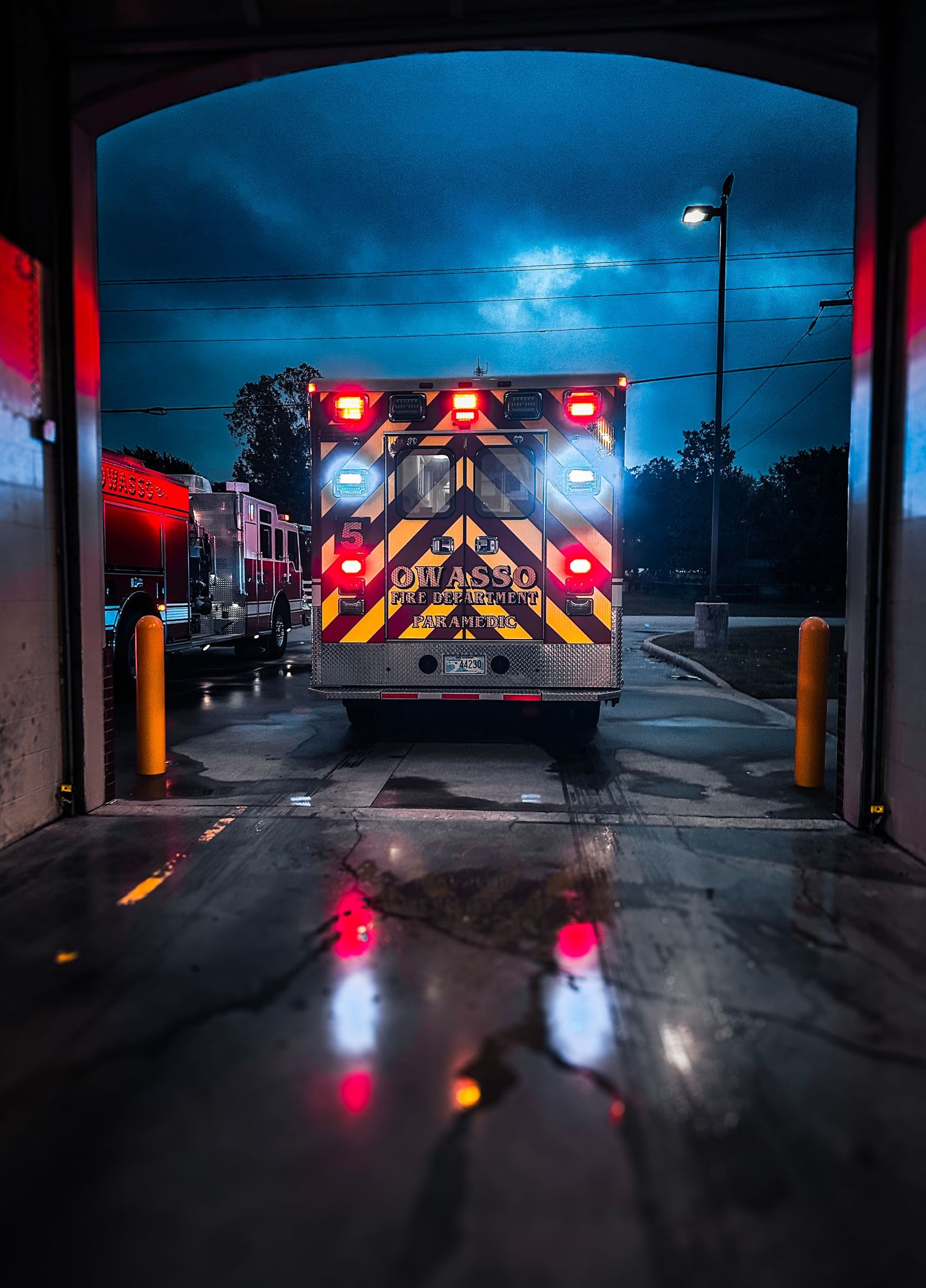 Fire truck with open compartments displaying hoses and firefighter gear at a fire station.