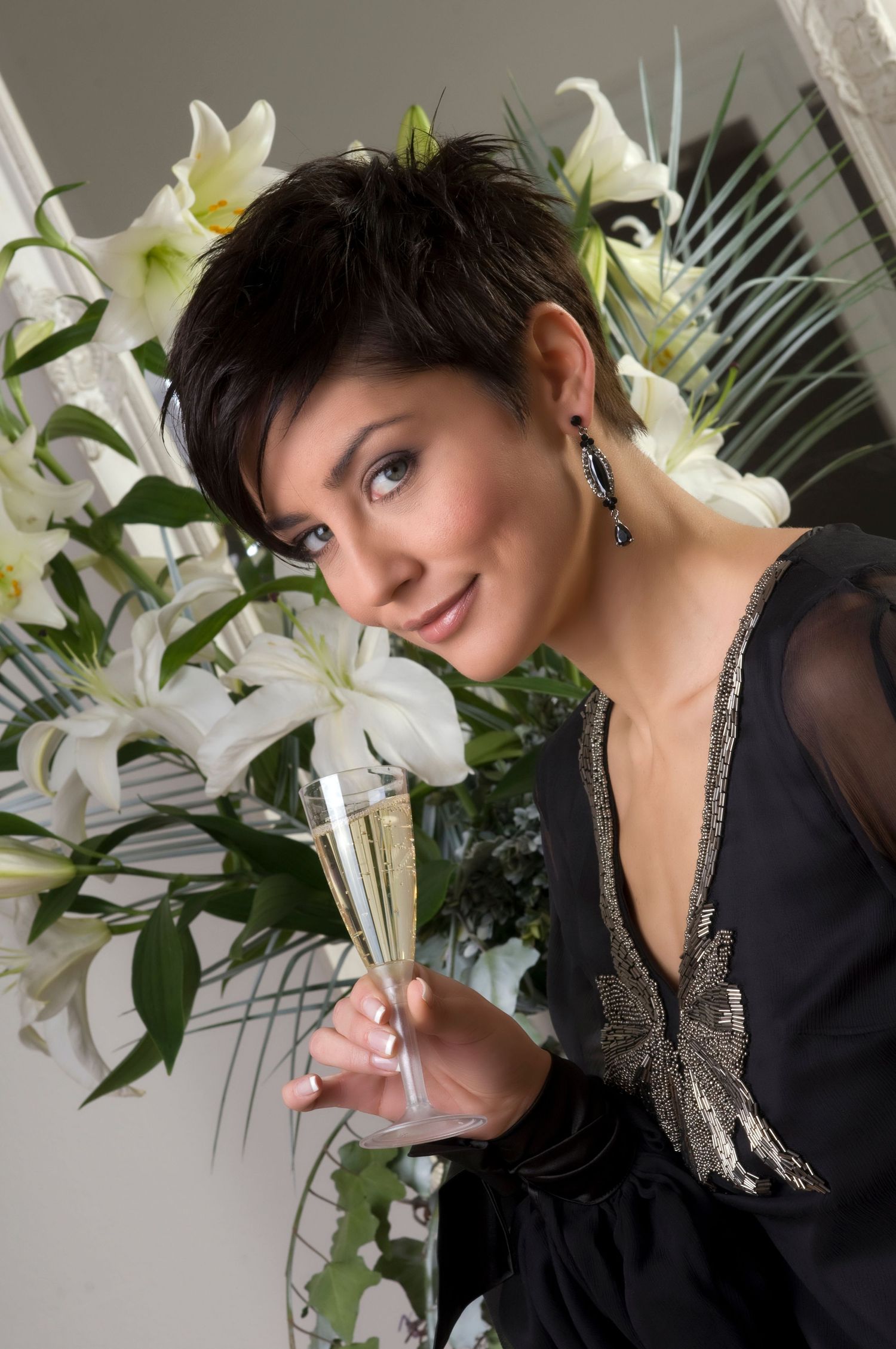Elegant portrait with white lilies featuring black cocktail dress and champagne glass.