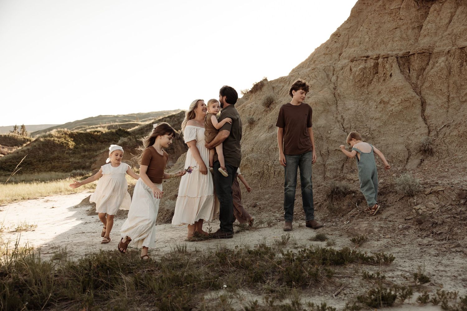 Large family posing together on sandy badlands trail at golden hour during a photoshoot in Central Alberta