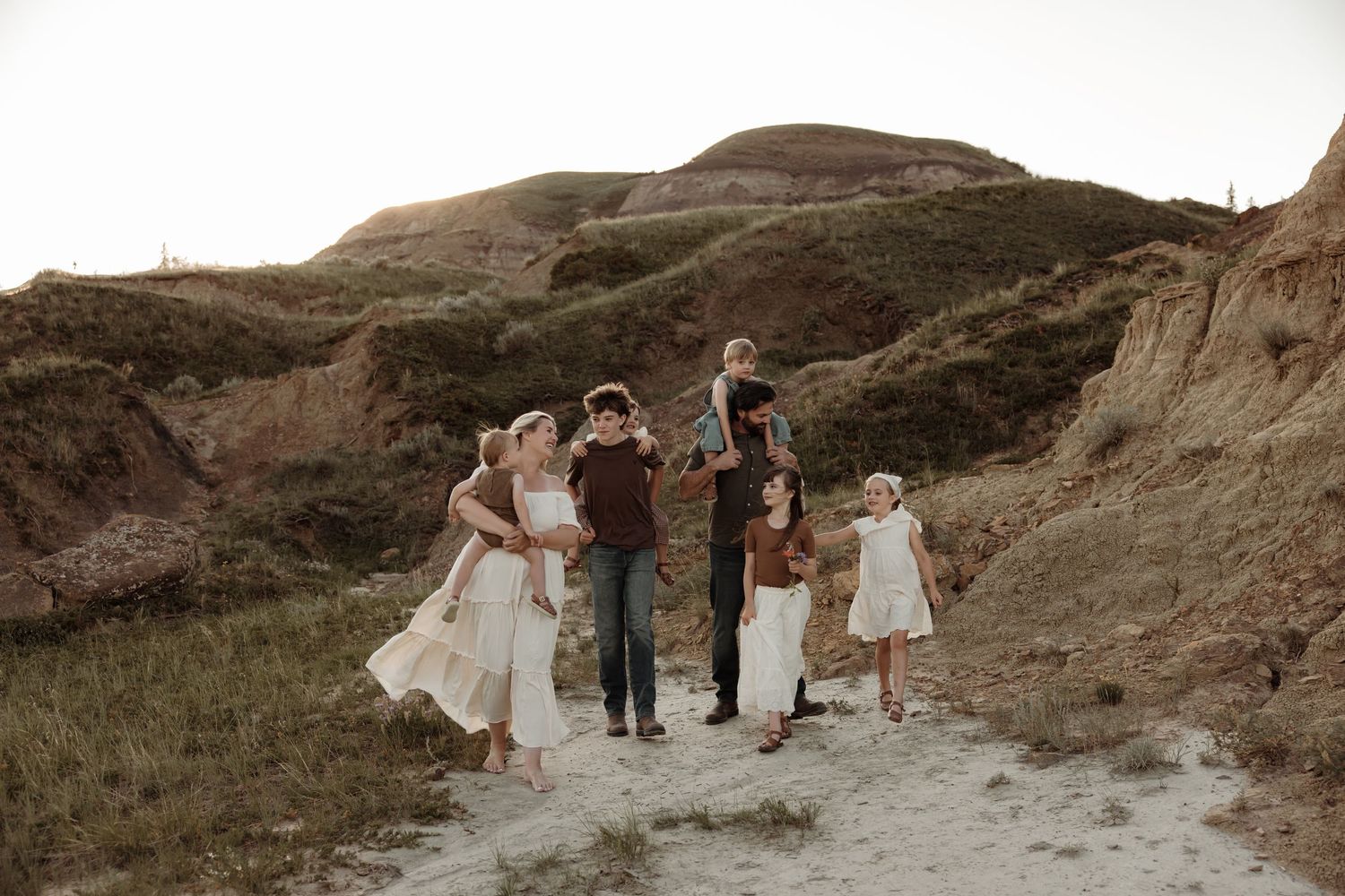 Family of six poses on a sandy desert trail while naturally being photographed for family pictures in calgary alberta
