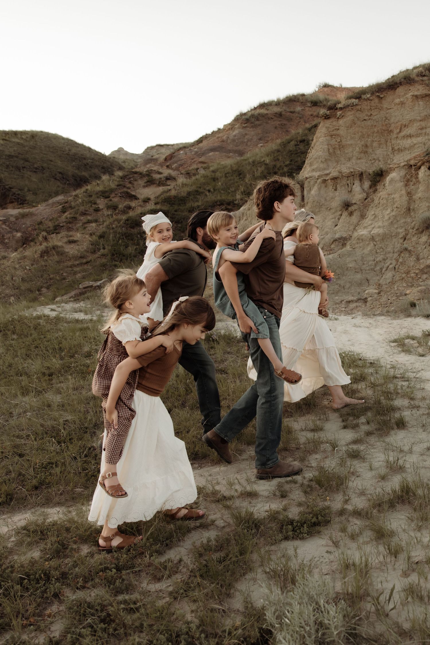 A family with young children walks through a scenic badlands landscape during a golden hour outdoor photo session.
