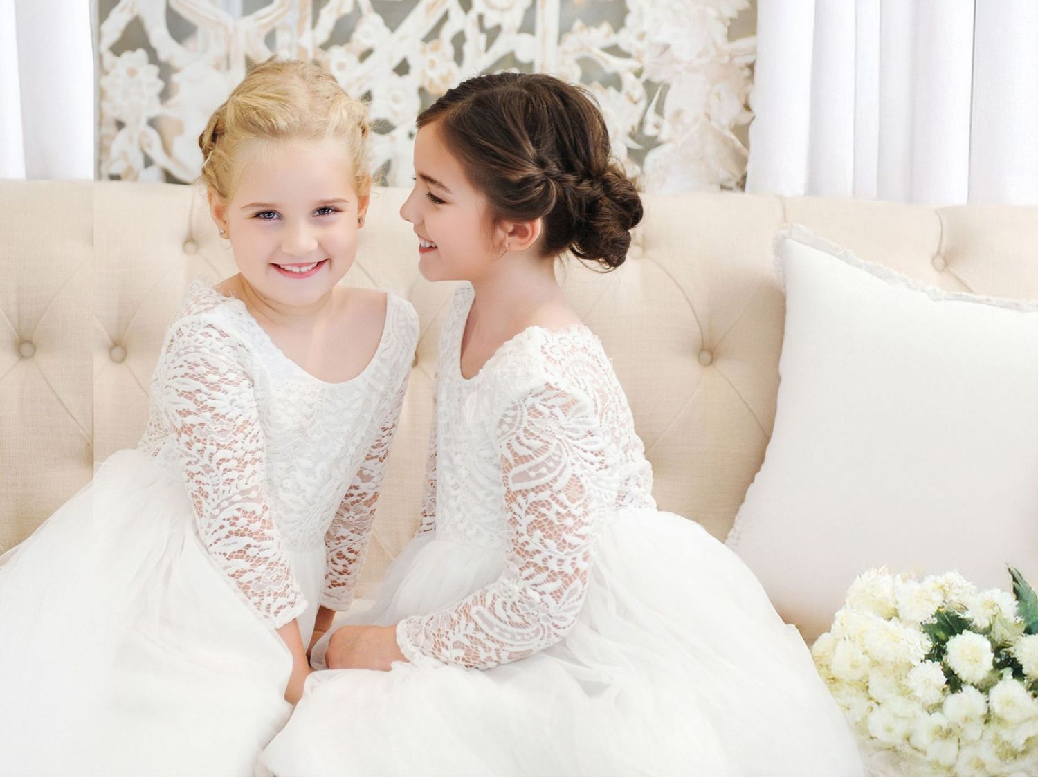 Bride in white ball gown with veil and bridesmaids in blush pink dresses posing in elegant columned venue.