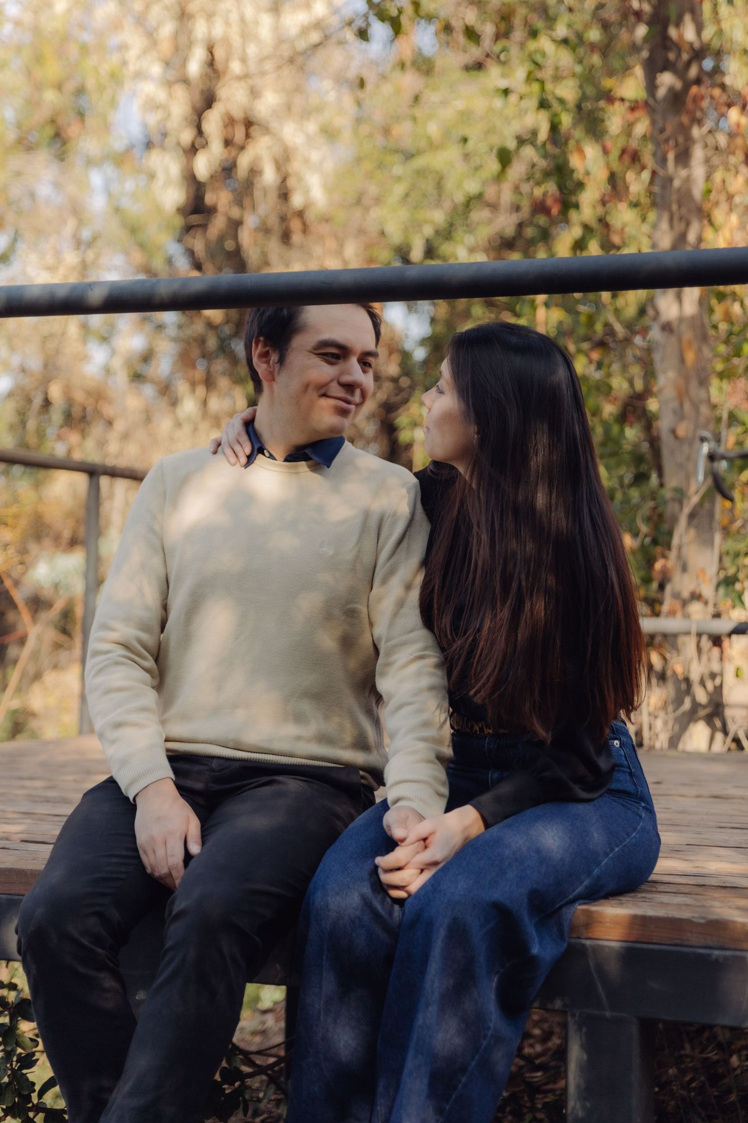 Couple sitting close together on a wooden bench in an autumn park setting.