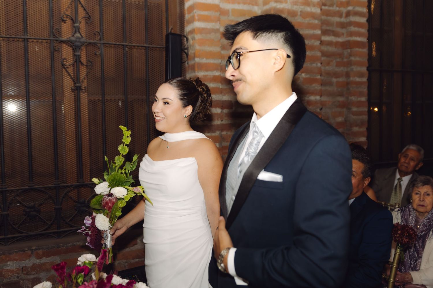 Bride and groom stand together at the altar during their elegant indoor wedding ceremony.