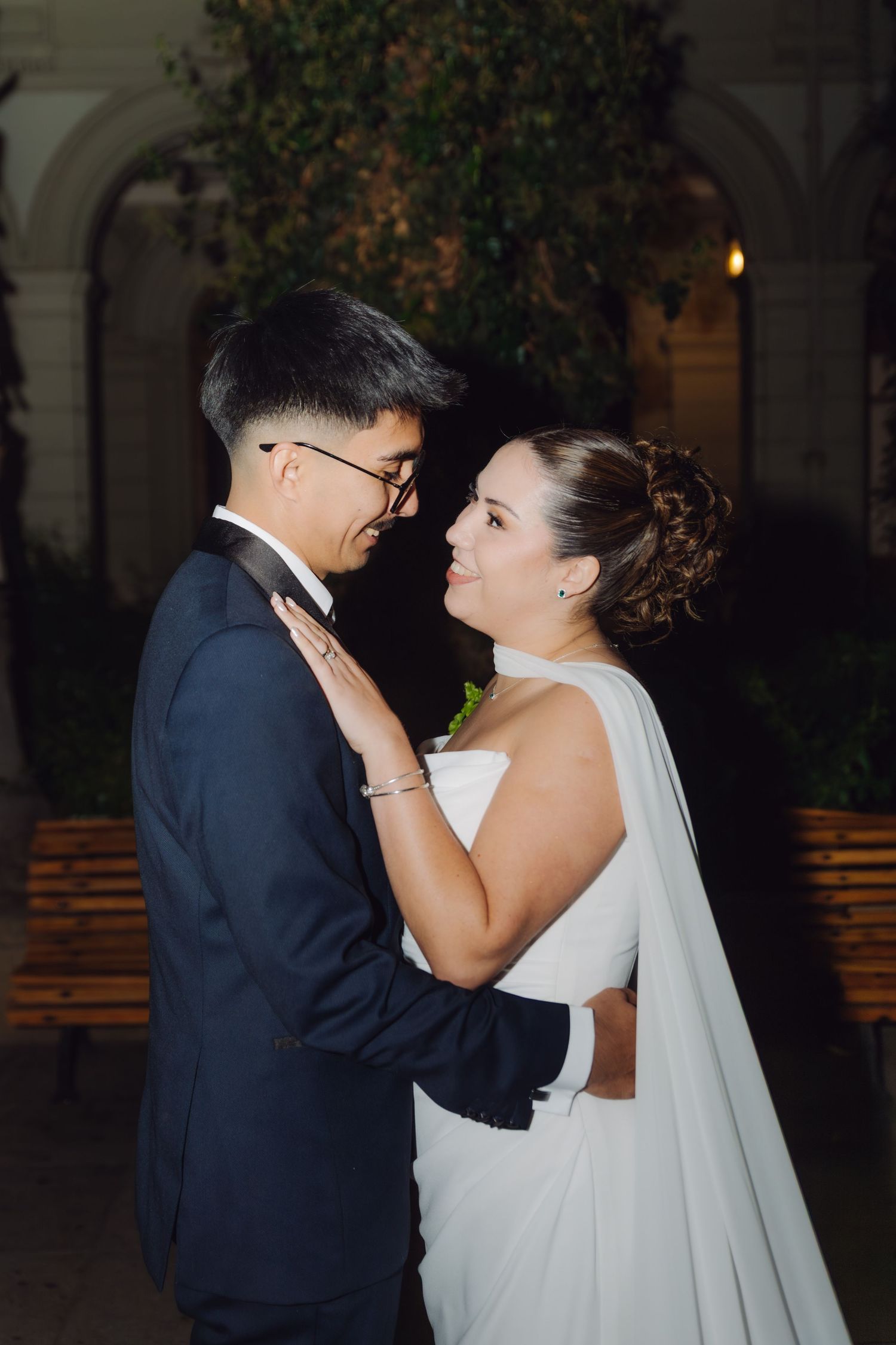 Bride and groom share an intimate moment gazing into each other's eyes during their wedding night portrait session.