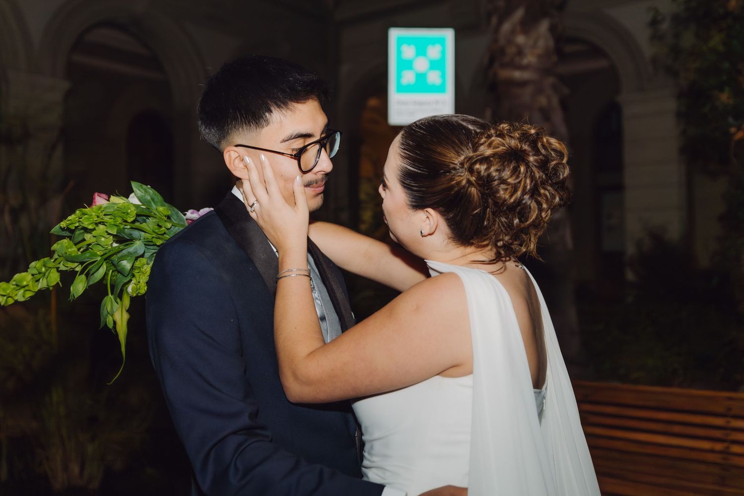 Bride tenderly cups groom's face in her hands during an intimate outdoor wedding night moment.