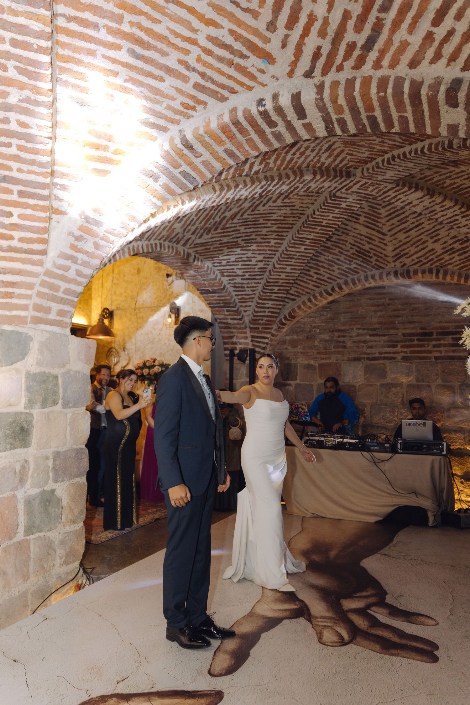 Bride and groom share first dance under stunning brick vaulted ceiling at wedding reception.
