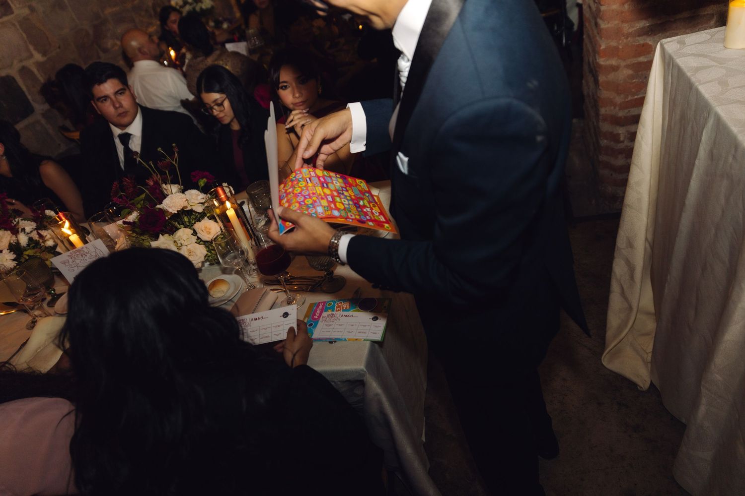 Wedding guests playing bingo game at elegantly decorated reception dinner table.