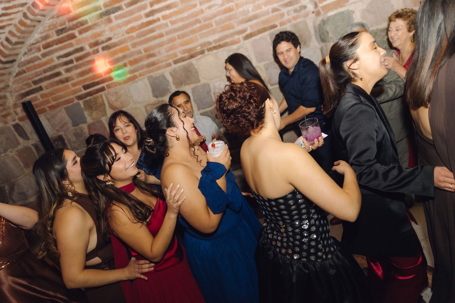 Guests dancing and celebrating joyfully at a lively wedding reception party in a brick venue.