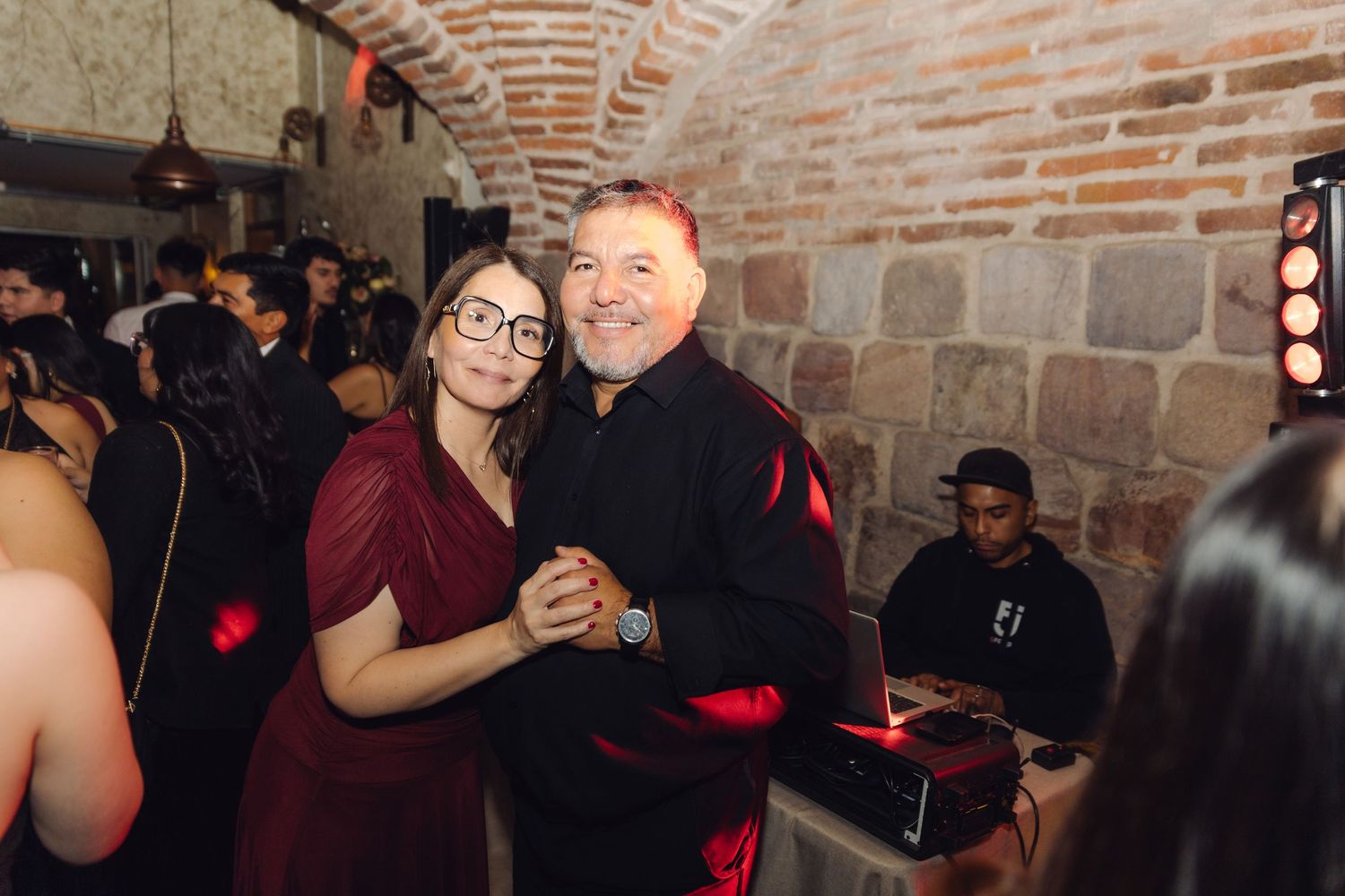 Couple slow dancing together at a wedding reception, woman in burgundy dress, man in black jacket.