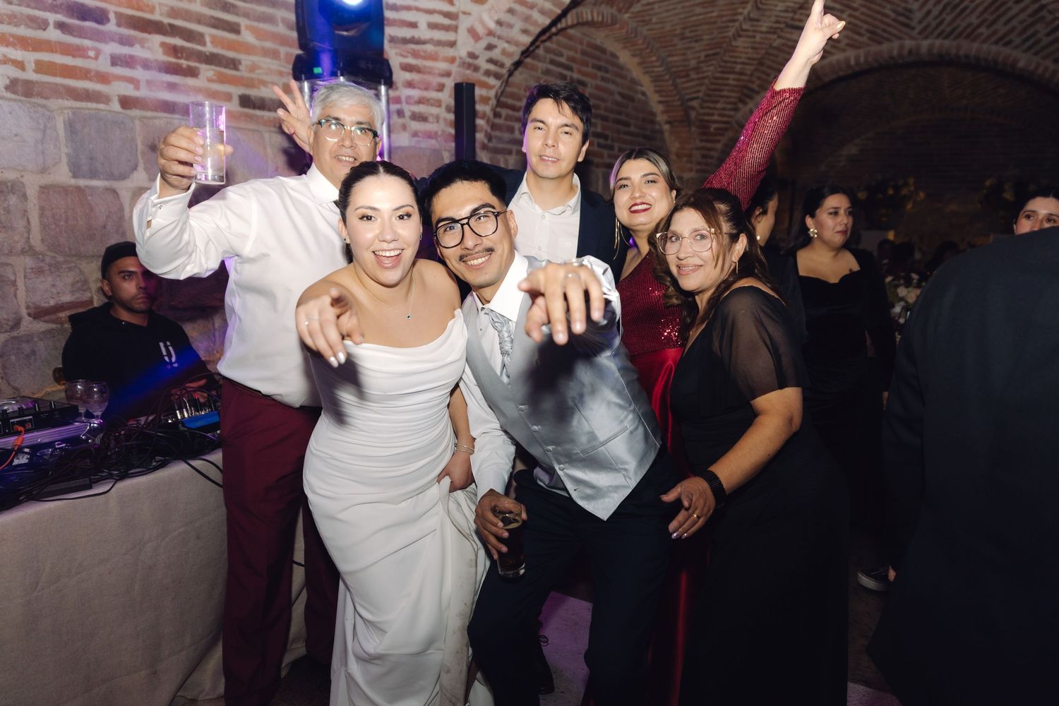 Bride and groom celebrating with family and friends under festive lights at their wedding reception.