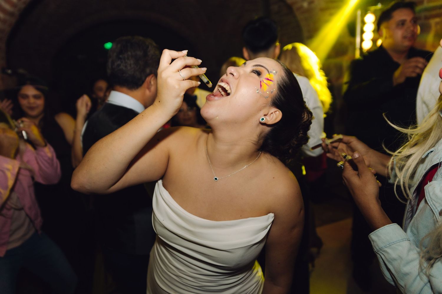 Excited bride enjoys food and drinks while celebrating on the wedding reception dance floor.