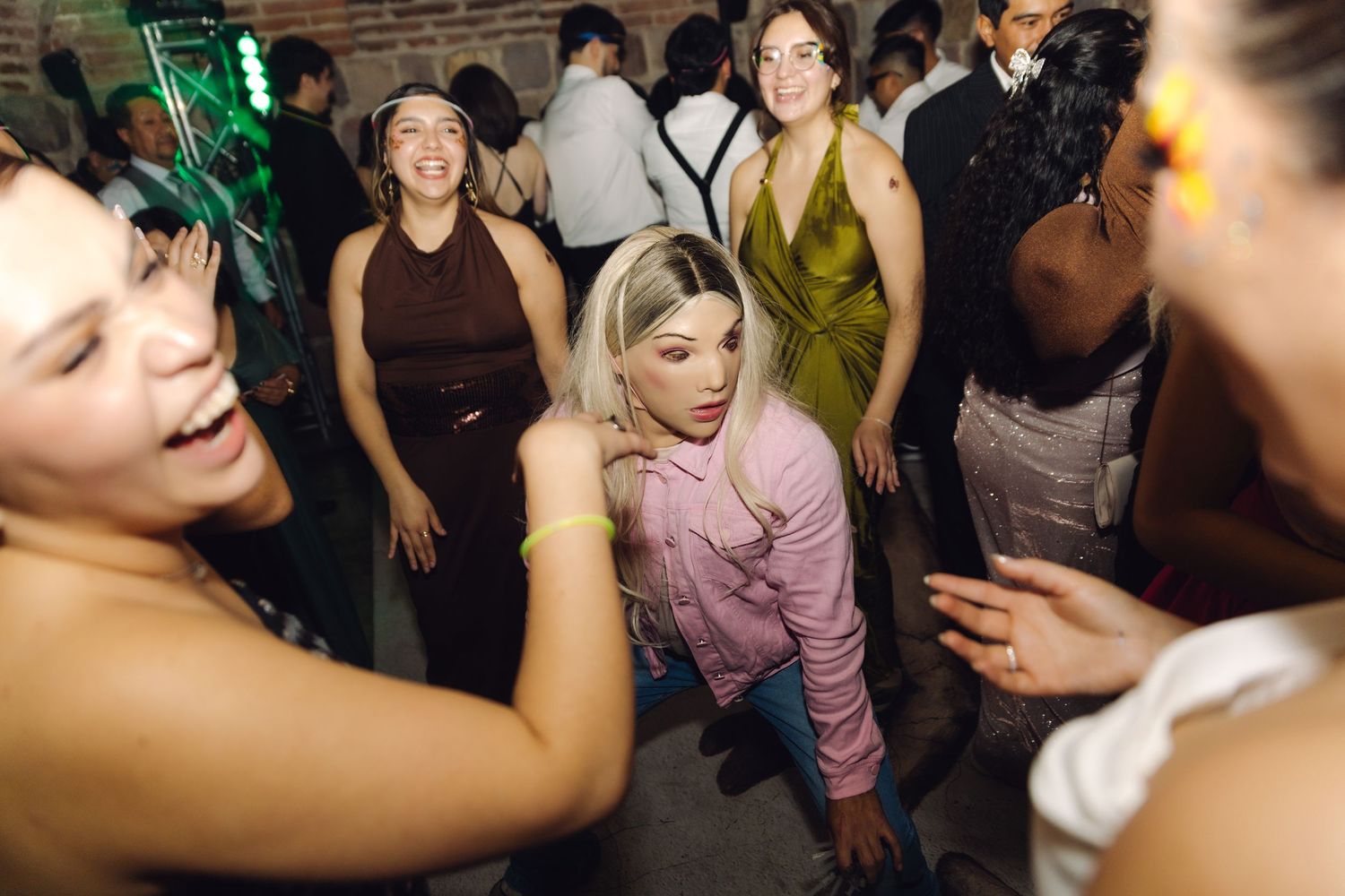 Group of women smile and dance together at a festive wedding reception party.