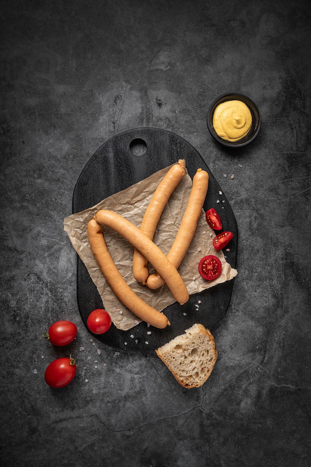 Mangalica frankfurter sausage by Fekete Zsóka in a moody dark flatlay with rustic wood and stone styling, © Reka Peurala, Three Pod Studio