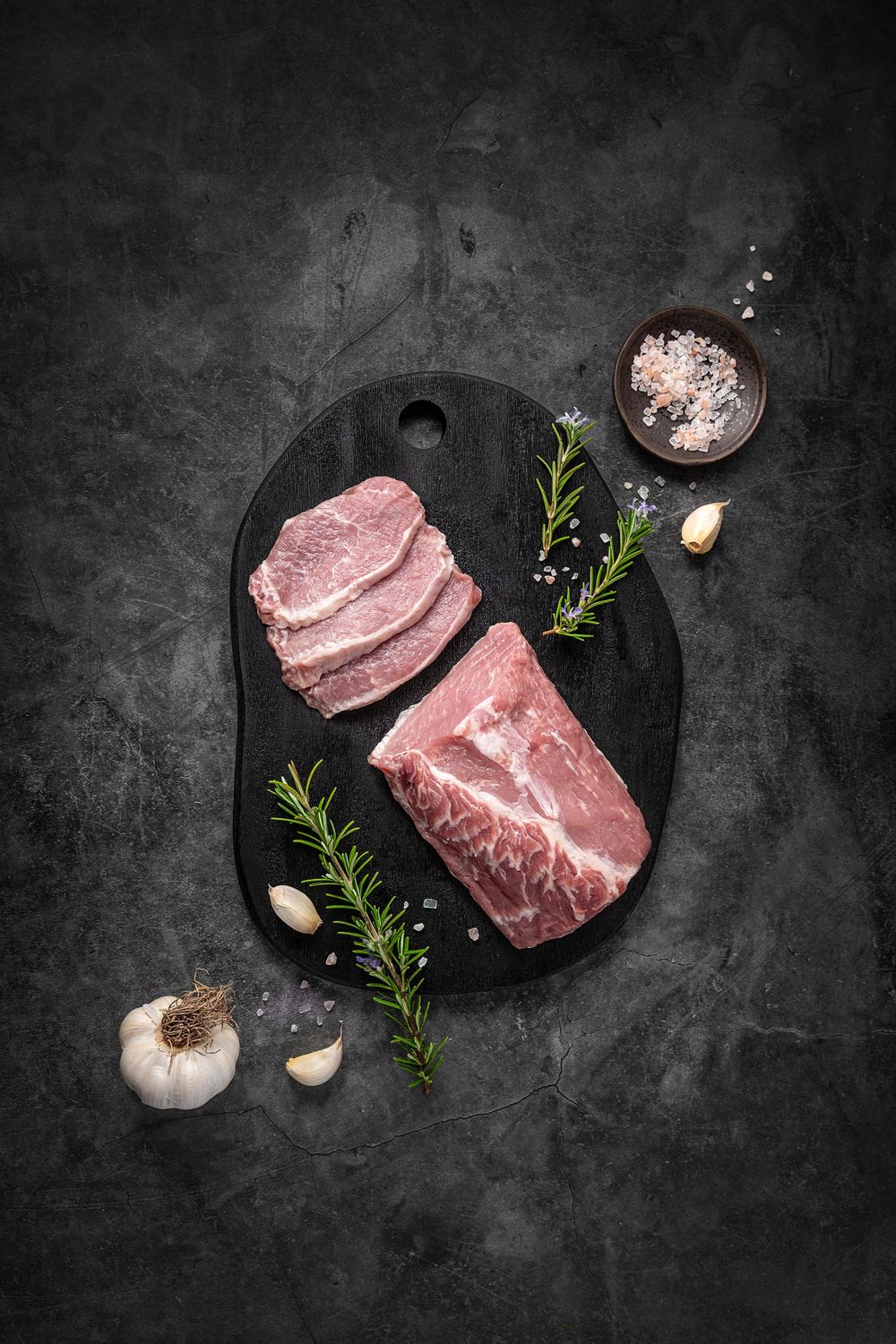 Mangalica pork loin fillet by Fekete Zsóka in a moody dark flatlay with rustic wood and stone styling, © Reka Peurala, Three Pod Studio