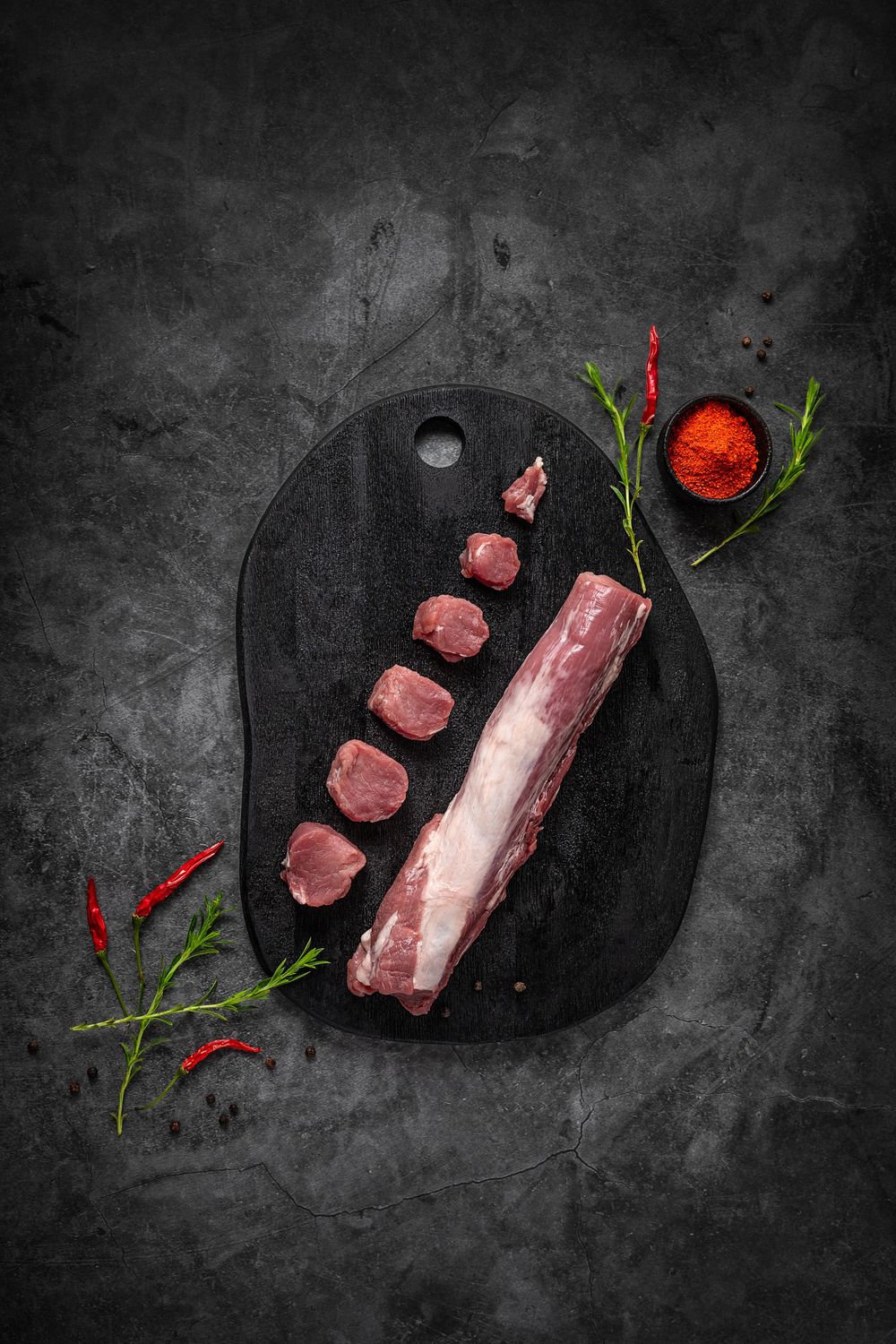Mangalica pork tenderloin by Fekete Zsóka in a moody dark flatlay with rustic wood and stone styling, © Reka Peurala, Three Pod Studio