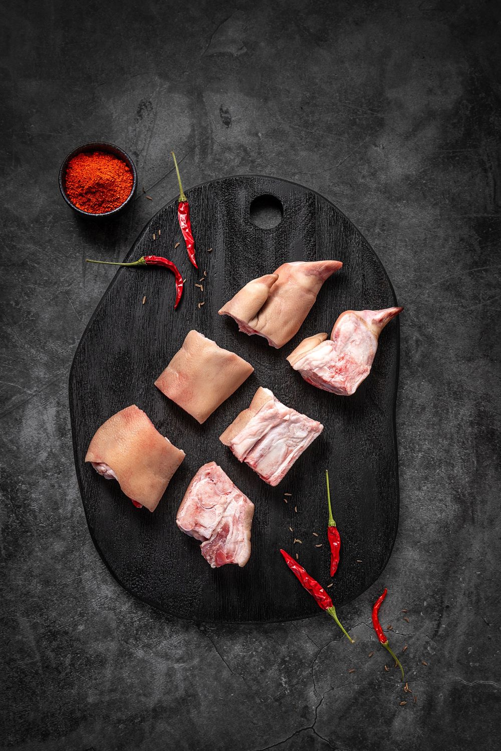 Mangalica pork trotter by Fekete Zsóka in a moody dark flatlay with rustic wood and stone styling, © Reka Peurala, Three Pod Studio