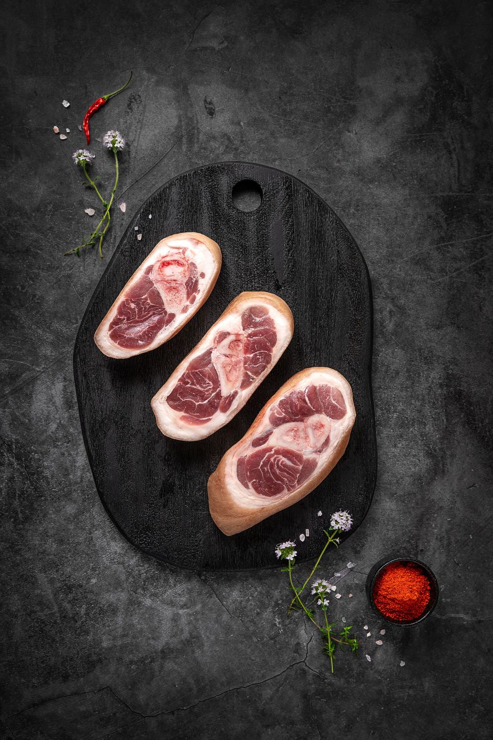 Sliced mangalica pork knuckle with bone by Fekete Zsóka in a moody dark flatlay, © Reka Peurala, Three Pod Studio