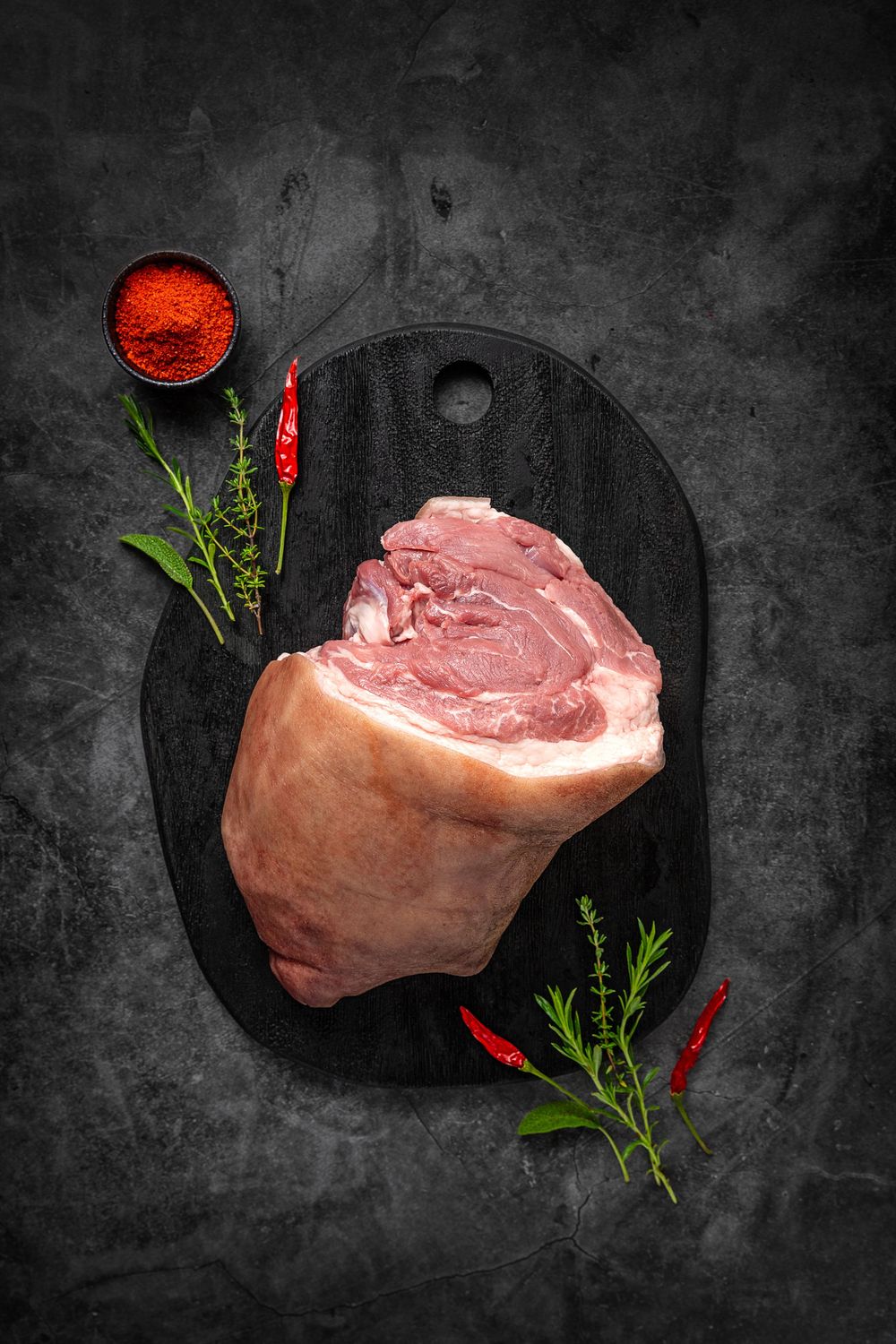 Boneless mangalica pork knuckle by Fekete Zsóka in a moody dark flatlay with rustic wood and stone styling, © Reka Peurala, Three Pod Studio