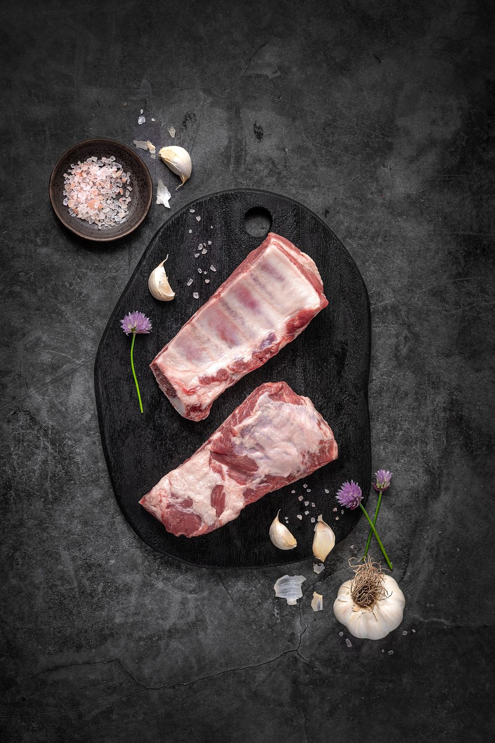 Mangalica pork ribs by Fekete Zsóka in a moody dark flatlay with rustic wood and stone styling, © Reka Peurala, Three Pod Studio