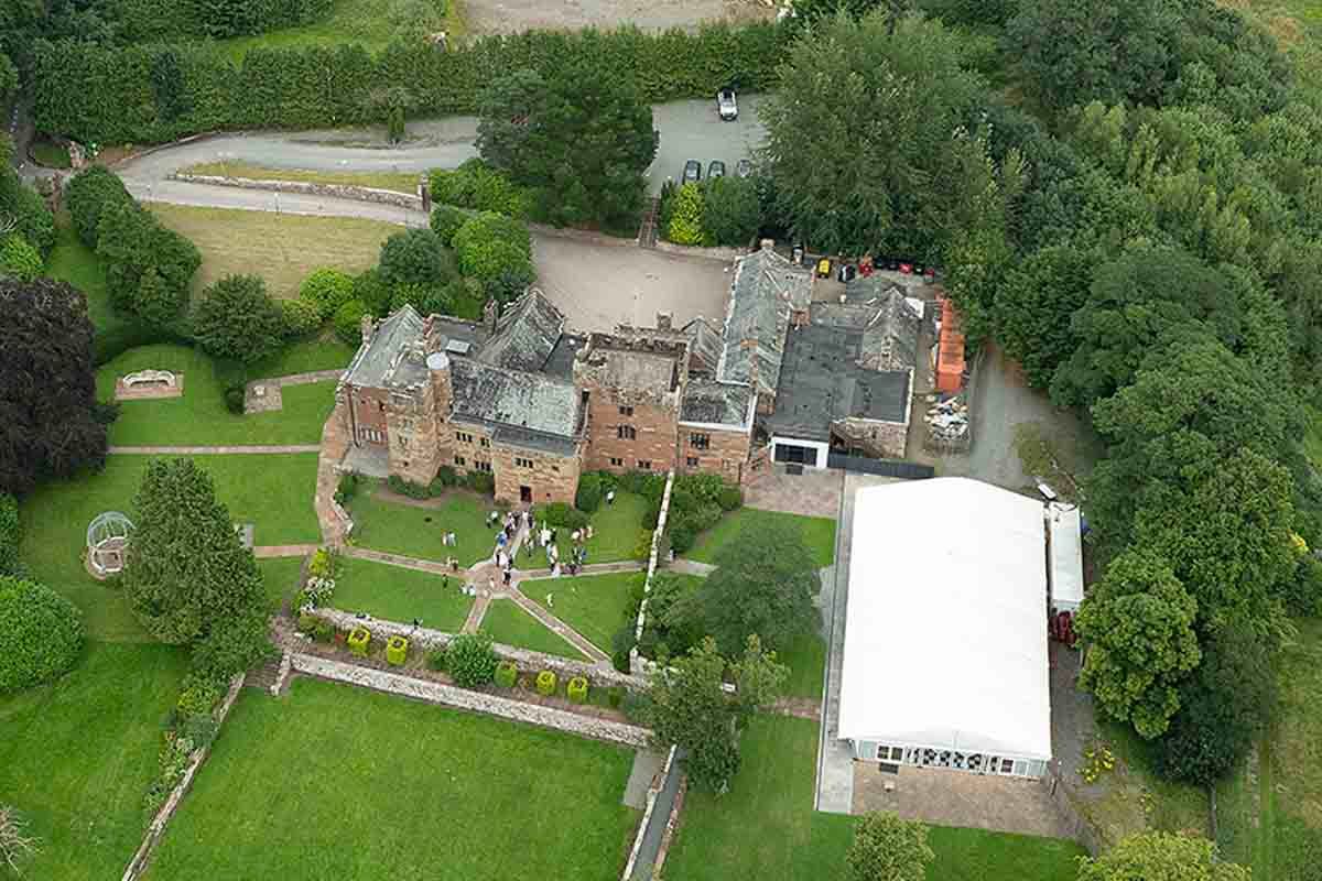 Aerial view of a Dalston Hall estate surrounded by lush green trees and manicured gardens.