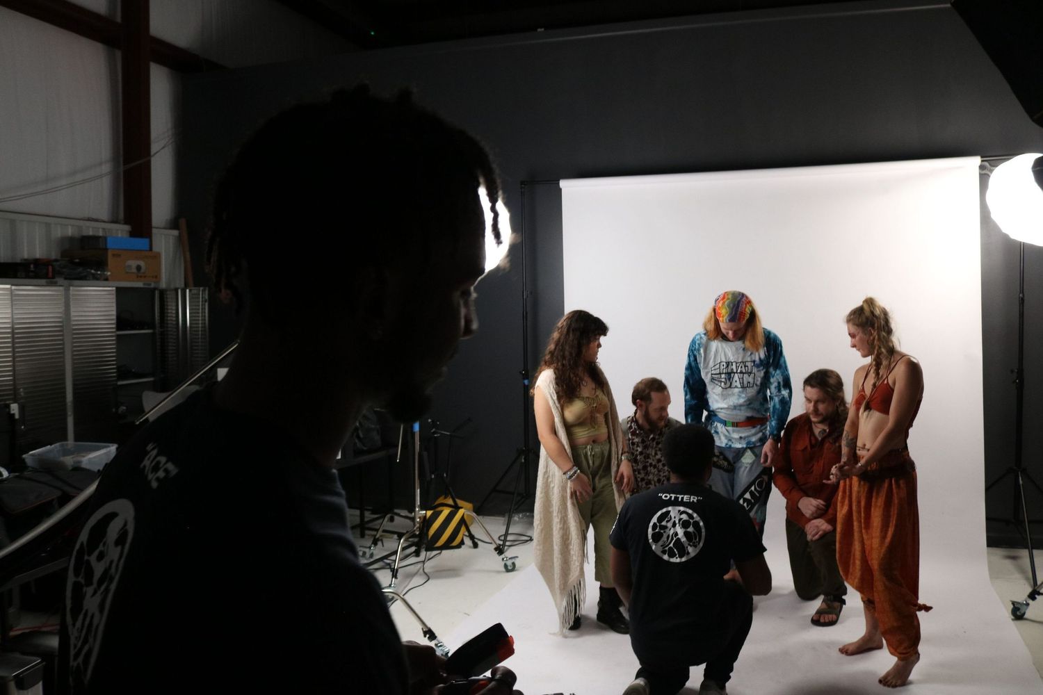 Behind-the-scenes photo shoot with group of models posing in bright white studio space.